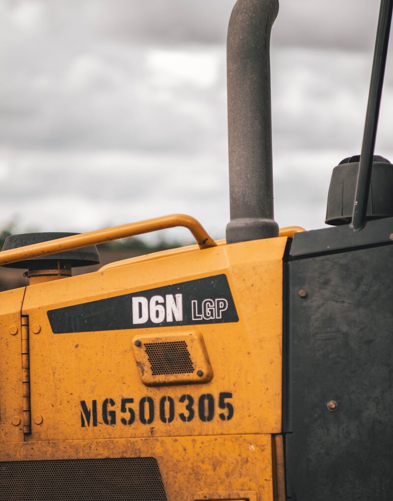 the front of a yellow bulldozer parked on the side of a road